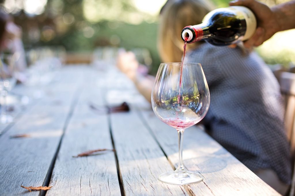 Pouring a glass of red wine outsite on a picnic bench