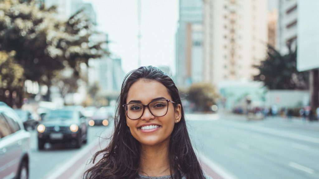 Young woman with glasses smiling in the city