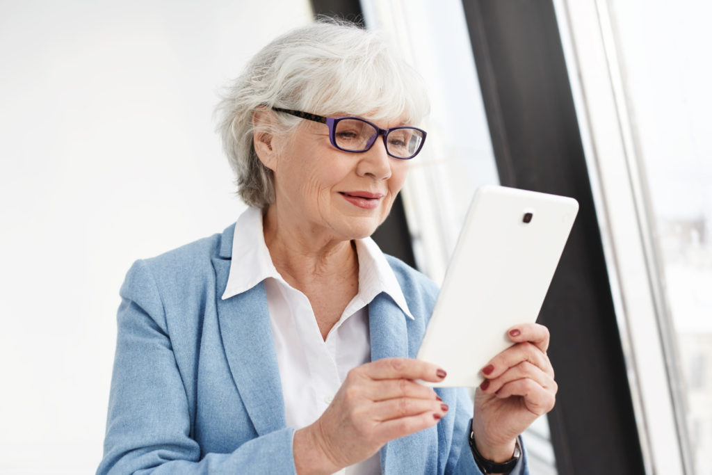 Elderly woman suffering from presbyopia trying to read the screen of her tablet