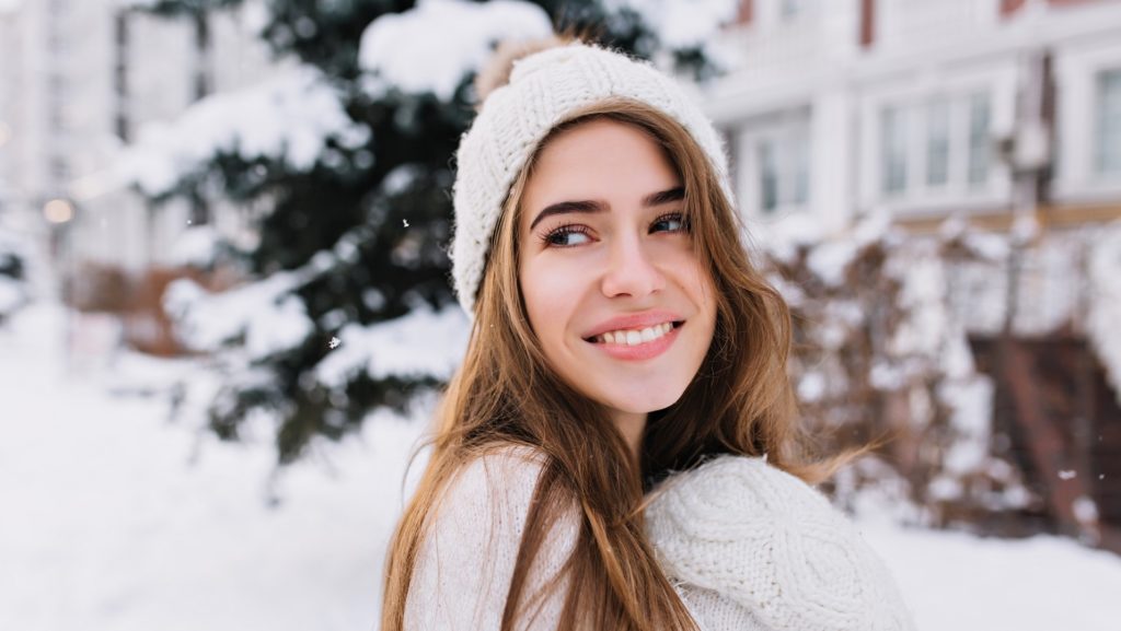 Woman wearing a toque smiling outside on a winter day