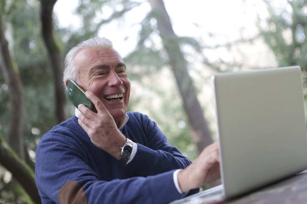 Older man wearing a long sleeve shirt using digital gadgets.