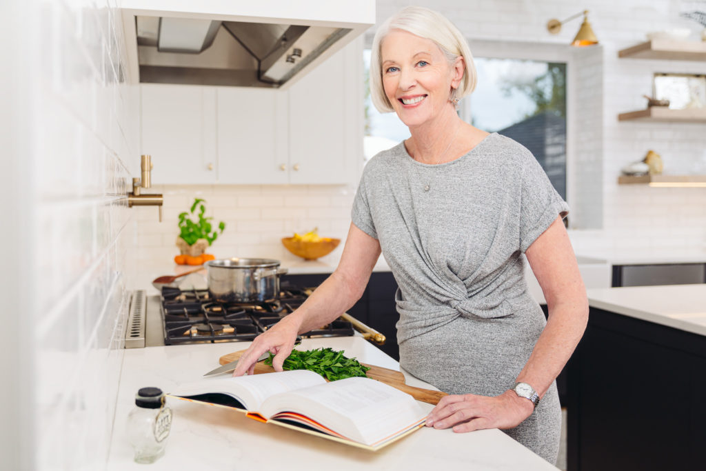 Woman reading a cook book in her kitchen without any issues after having surgery to treat hyperopia