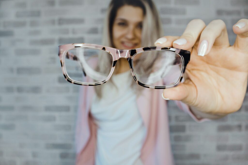 Woman holding her glasses up to the camera