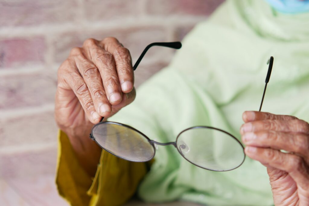 senior holding glasses